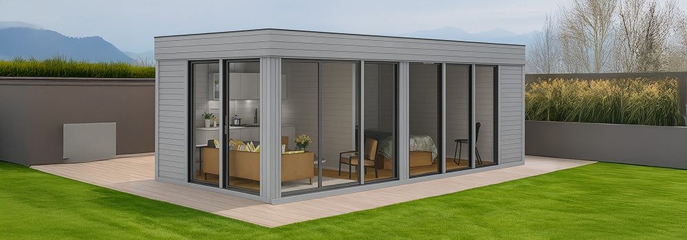 Modern grey garden room with floor-to-ceiling windows revealing lounge and bedroom areas.