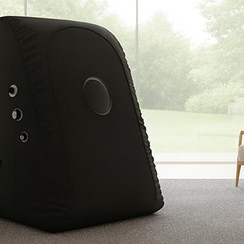 Vertical inflatable hyperbaric oxygen chamber in a serene minimalist lounge with modern furnishings and large garden-view windows.