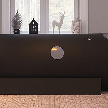 Hyperbaric oxygen chamber in a cozy, softly lit living room with grey walls, framed artwork, and decorative elements near a double window.