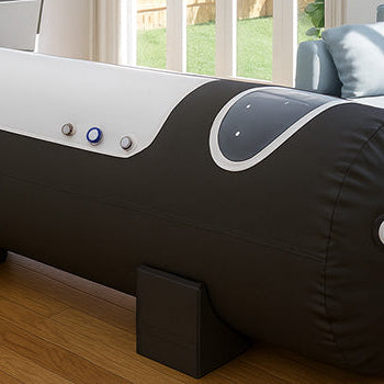 Hyperbaric oxygen chamber in a bright home interior with wood flooring, light blue sofa, and dining area, illuminated by natural light from garden-facing windows.