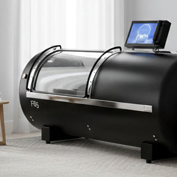 Hyperbaric oxygen therapy chamber in a private wellness room with beige walls, wood flooring, and connected oxygen units..