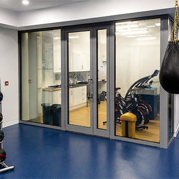 Hypoxic therapy and altitude training facility with exercise bikes, gym equipment and a glass-enclosed training room.