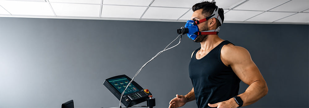 Athlete wearing a breathing mask during Hypoxic Therapy performance training on a treadmill with monitoring equipment.