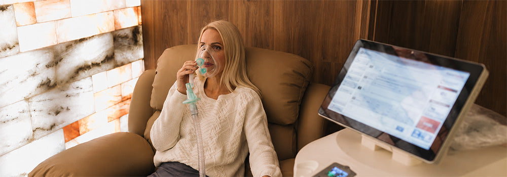 Woman using a ReOxy breathing mask during a relaxing Hypoxic Therapy session with specialist intermittent hypoxic treatment equipment.