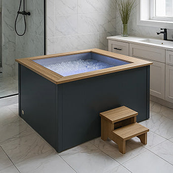 Modern indoor ice bath with wood trim in an elegant marble bathroom.