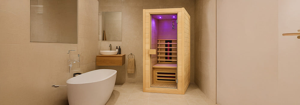 Compact infrared sauna with purple lighting in a modern luxury bathroom with tub and vanity.