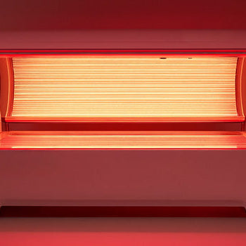 Red light therapy bed glowing in a minimalist studio with sleek design and soft lighting.