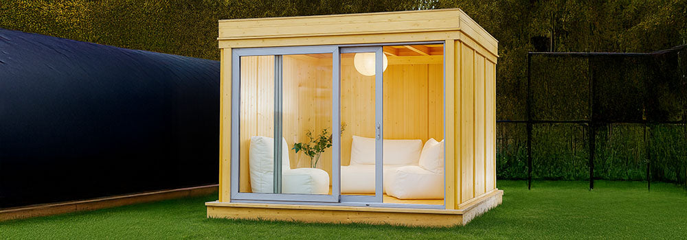 Cozy light wood garden room with sliding glass doors and white sofa seating at dusk.