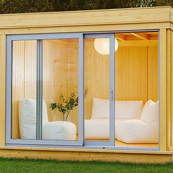 Cozy light wood garden room with sliding glass doors and white sofa seating at dusk.