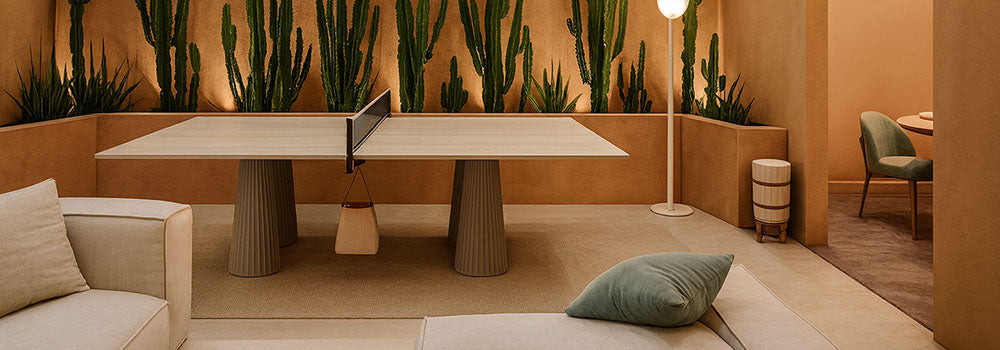 lightwood ping pong table in a desert-style lounge with sculptural cacti, soft lighting, and neutral furnishings.