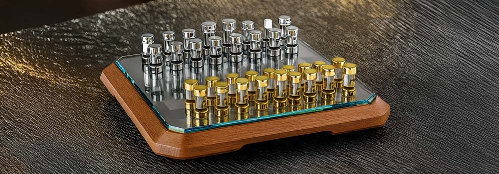 Luxury glass chess set with gold and silver pieces on a rippled metallic surface.