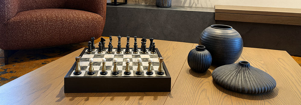 Luxury black and white chess set with gold accents on oak table in modern living room.