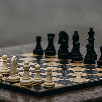 Elegant wooden chess set on a rain-soaked stone table in a quiet urban park.