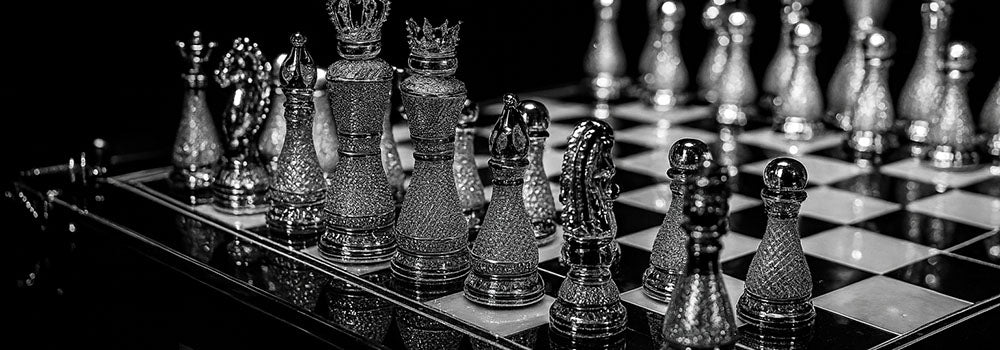 Luxury crystal-studded chess set on reflective board under dramatic lighting in black-and-white.