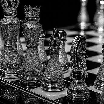 Luxury crystal-studded chess set on reflective board under dramatic lighting in black-and-white.