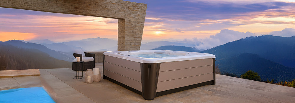 Luxury hot tub on a stone patio overlooking mountain views at sunset.