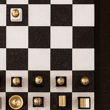 Modern gold and silver luxury chess set on a black coffee table with snacks and drinks for game night.