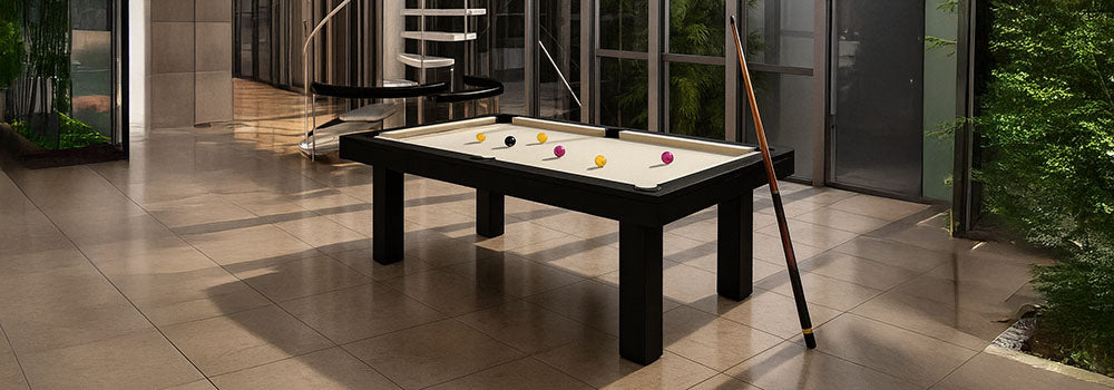 modern atrium with glass walls and white spiral staircase featuring black pool table with cream felt.