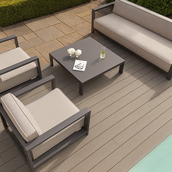 modern beige outdoor lounge set on light wood deck beside pool and stone patio.