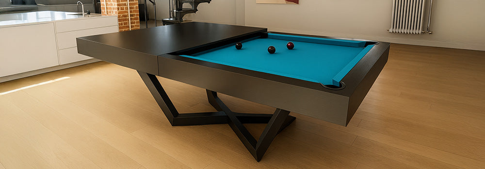 black modern pool table with bright turquoise felt in an industrial loft featuring spiral staircase, brick column, and abstract art.