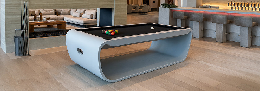 ultra-modern curved pool table in a luxury open-plan lounge with fireplace and cocktail bar.