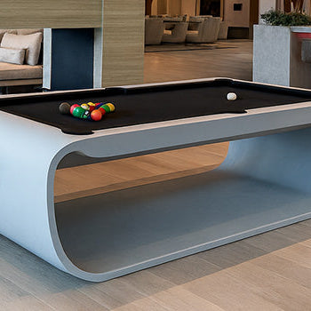 ultra-modern curved pool table in a luxury open-plan lounge with fireplace and cocktail bar.