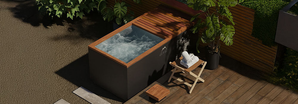 Modern rectangular ice bath in a private garden corner with wooden deck, lush plants, and slatted fence.