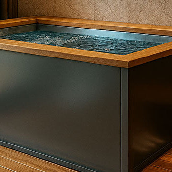 Modern ice bath in luxurious spa room with wooden floors, soft lighting, and towel shelving.