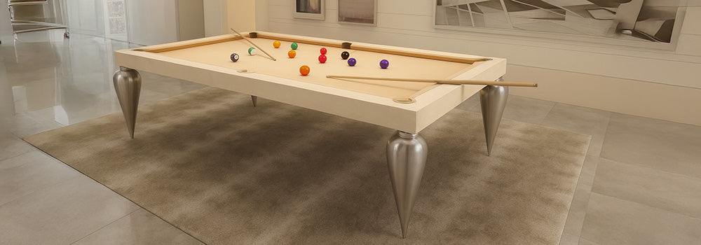 modern light wood pool table with metallic cone legs in a neutral-toned interior with pendant lighting and abstract wall art.