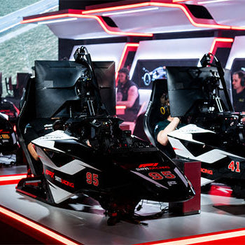 Multi-rig racing simulator centre with drivers, Fanatec equipment and Formula-style cockpits arranged for competitive esports motorsport racing.