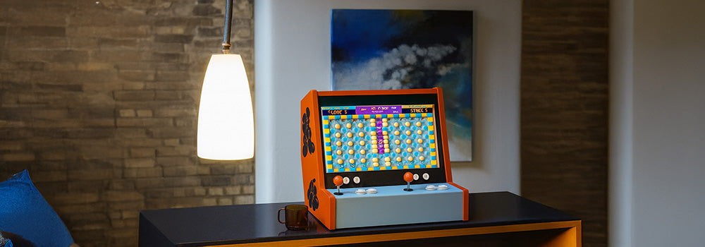 orange and blue arcade machine with puzzle game screen on a dark countertop in a modern loft interior.