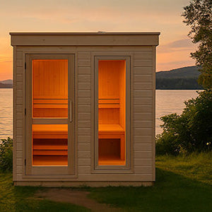 Front-facing wooden outdoor sauna by lakeside at sunset with warm glowing interior and scenic mountain backdrop.