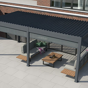 Stylish grey pergola with lounge seating on a large tiled patio beside a modern red brick house.