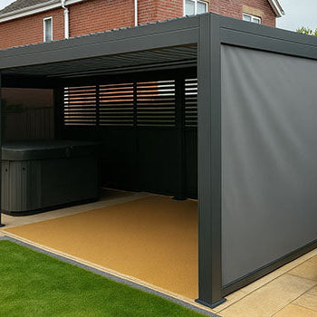Grey pergola with privacy screens sheltering hot tub on patio beside suburban home.
