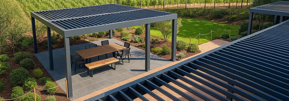 Modern louvered pergola over outdoor dining area beside vineyard under blue sky.