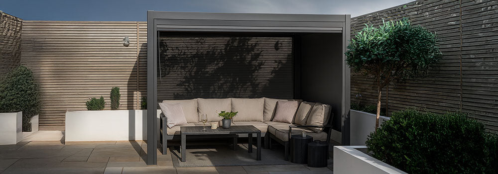 Modern pergola with beige L-shaped sofa and neutral patio styling in a private walled garden.