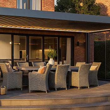 Sleek pergola with outdoor dining table beside brick house and manicured lawn.