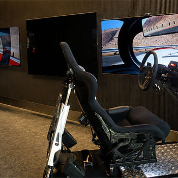 Professional motion racing simulator cockpits with racing seats, steering wheels and immersive triple-screen displays in a dedicated sim racing room.