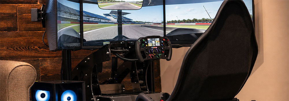 Racing simulator cockpit with triple monitors, motorsport steering wheel and racing seat for an immersive virtual track driving experience.