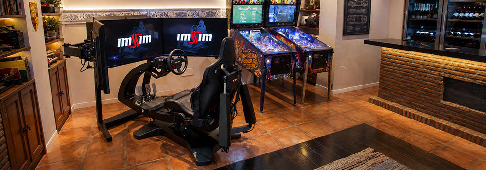 Racing simulator lifestyle setup with dual screens, racing seat and steering wheel in a luxury home games room with arcade machines.