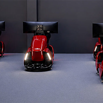 Five red professional racing simulator cockpits with integrated seats, steering controls and widescreen monitors in a sim racing room.