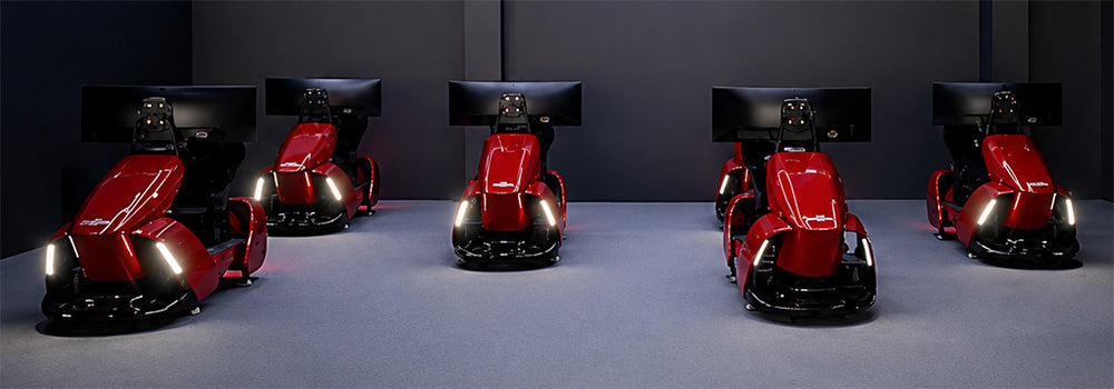 Five red professional racing simulator cockpits with integrated seats, steering controls and widescreen monitors in a sim racing room.