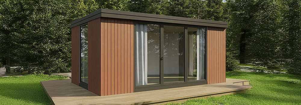 Modern red cedar garden room with sliding glass doors on a wooden deck surrounded by pine trees.
