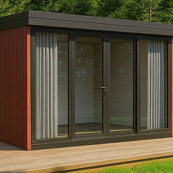 Contemporary red garden room with dark frame glass doors on a wooden deck surrounded by forest greenery under a clear blue sky.