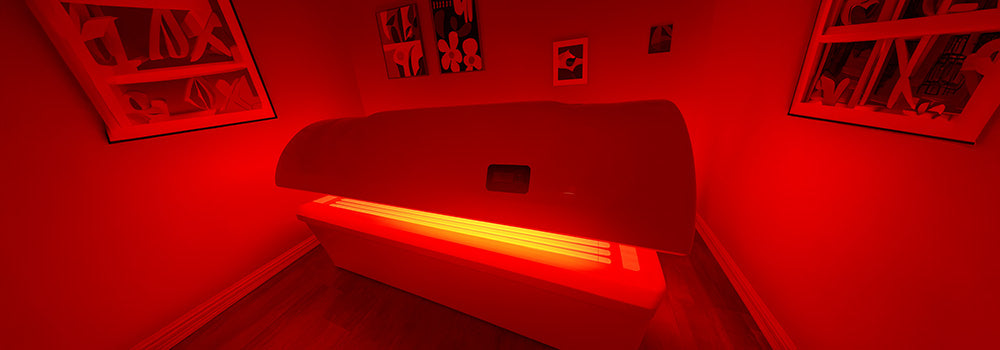 Glowing red light therapy bed in art-filled room with warm wooden floors.