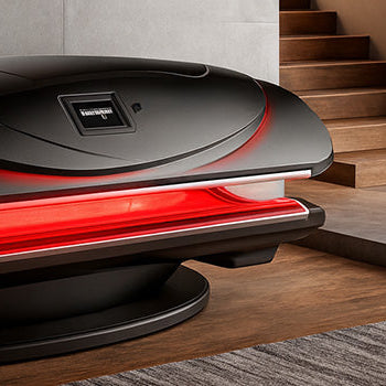 Luxury red light therapy bed in a modern home with concrete walls, wood stairs, and snowy mountain view.