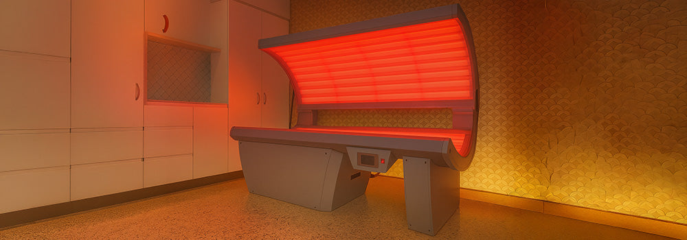red light therapy bed glowing in a modern interior with white cabinets and patterned wallpaper.