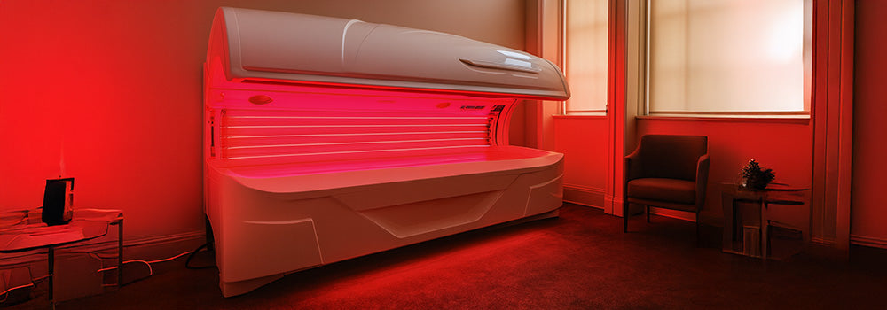 Red light therapy bed glowing in a peaceful wellness room with natural window light and armchair.