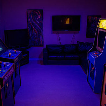 retro arcade room with rows of classic game machines lit by purple LED ceiling lights and vibrant screen displays.