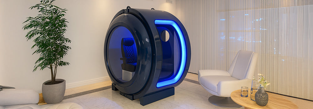 Modern spherical hyperbaric oxygen chamber with blue LED lighting in a luxury wellness lounge featuring marble floors, minimalist furniture, and ambient lighting.